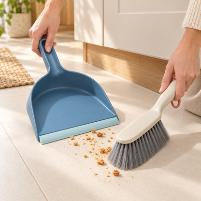 Compact dustpan and brush sweeping dry crumbs from a kitchen floor